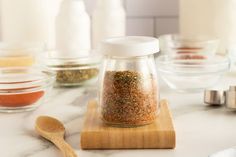 a wooden spoon sitting on top of a counter next to jars filled with different types of spices