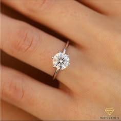 a woman's hand with a diamond ring on top of her finger, showing the center stone