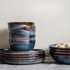 a stack of blue bowls sitting next to each other on top of a white table