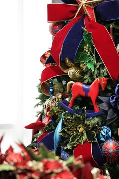 a decorated christmas tree with red, white and blue ribbons on it's top