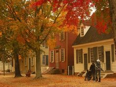 two people standing in front of a house with autumn leaves on the ground