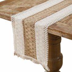 a wooden table topped with a white and brown table runner next to a wood post