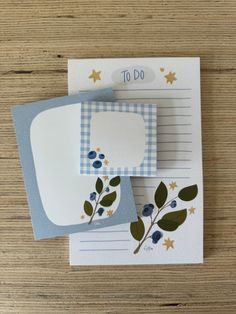 two cards with leaves on them sitting on top of a wooden table next to each other