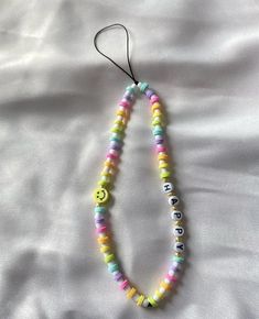 a colorful beaded necklace is hanging on a white sheet with the word smile spelled in small letters