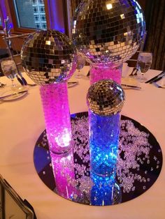 two disco ball vases on a table with purple and blue lights