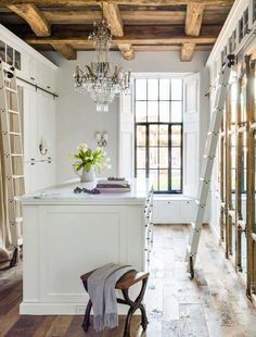 a kitchen with white cabinets and wooden floors, chandelier hanging from the ceiling