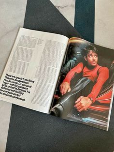 an open magazine on the floor next to a black and white striped rug with a man in red shirt