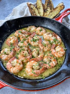 a skillet filled with shrimp and vegetables on top of a wooden cutting board