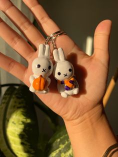 a hand holding two keychains that look like bunnies with carrots on them