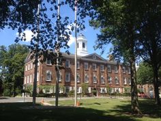 an old brick building with a steeple on top and trees in front of it