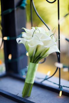 a bouquet of white flowers sitting on top of a window sill next to a wrought iron fence