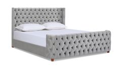 an upholstered bed frame with white pillows and pillow on the headboard is shown