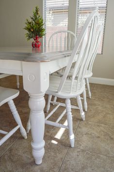 a white table with four chairs and a small potted plant on top of it