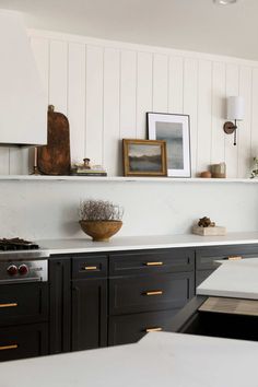 a kitchen with black cabinets and white counter tops is pictured in this image, there are pictures on the wall above the stove