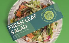 a fresh leaf salad on a white plate with a green label that says, fresh leaf salad