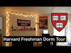 a dorm room with lights strung up on the wall and a harvard logo above it