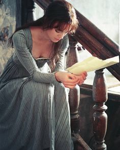 a woman is sitting on the stairs reading a paper