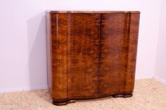 a large wooden cabinet sitting on top of a floor next to a wall with a plant in it