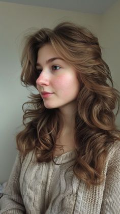 a woman with long brown hair wearing a sweater