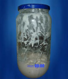 a glass jar filled with liquid on top of a blue background