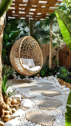 a swing chair in the middle of a garden with rocks and plants around it, hanging from a pergolated roof