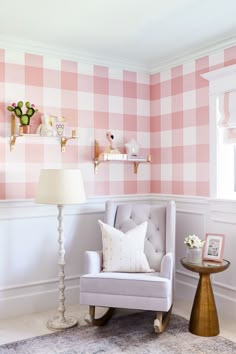 a pink and white checkered wall in a living room with a chair, lamp and table