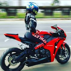 a man riding on the back of a red motorcycle