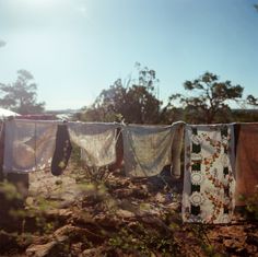 clothes hanging out to dry on a line in the dirt near some trees and bushes