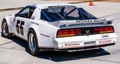 a white race car sitting on top of an airport tarmac