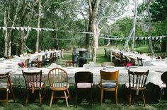 tables and chairs are set up for an outdoor wedding reception in the woods with bunting