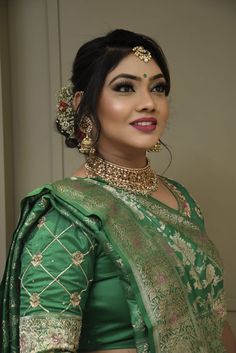 a woman in a green sari with gold jewelry on her neck and shoulders, posing for the camera