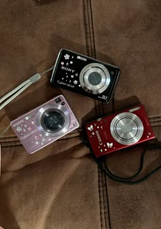 two cameras sitting next to each other on a bed