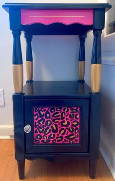 a black table with pink and yellow designs on the top is next to a white wall