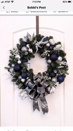 a christmas wreath hanging on the front door of a house with silver and blue ornaments