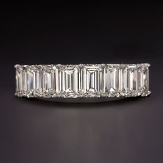 an emerald cut diamond ring on a black background