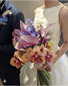 the bride and groom are holding bouquets of orchids in their hands as they stand next to each other