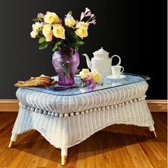 a wicker coffee table with flowers on it and a tea pot next to it