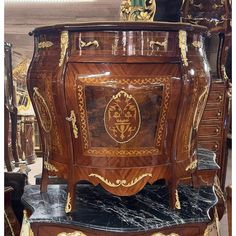 an ornate wooden dresser with marble top in a store display area, surrounded by other antique furniture