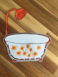 an orange flower in a white bowl on a wooden floor with a paper cut out of it