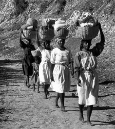 women carrying baskets on their heads down a dirt road