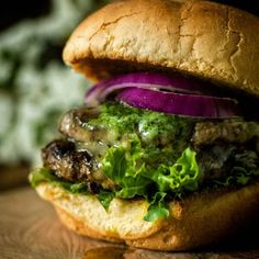 a hamburger with meat, lettuce and red onions