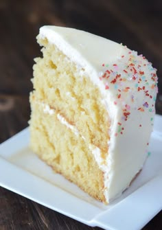 a slice of cake with white frosting and sprinkles