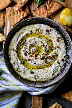 a bowl filled with white dip surrounded by crackers and lemons