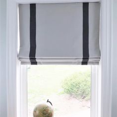 a window with a black and white striped roman blind in front of it, next to a globe on a windowsill