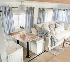 a living room filled with furniture and a wooden table in front of a window on top of a hard wood floor