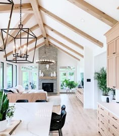 a large open concept living room and dining area with wood flooring, exposed beams, white walls, and wooden furniture