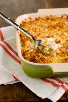 a green casserole dish filled with macaroni and cheese on a red and white towel