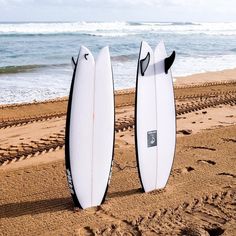 two surfboards are standing upright on the beach