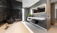 a modern bathroom with black marble walls and floor, along with a white bathtub