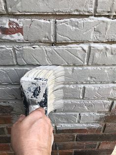 a person painting a brick wall with a paint brush